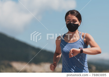 Determined fitness woman in short clothes wearing red protective face mask running outdoors in the city during coronavirus outbreak. Covid 19 and physical jogging activity, sport and fitness. Determined fitness woman in short clothes wearing red protective face mask running outdoors in the city during coronavirus outbreak. Covid 19 and physical jogging activity, sport and fitness. 78863895