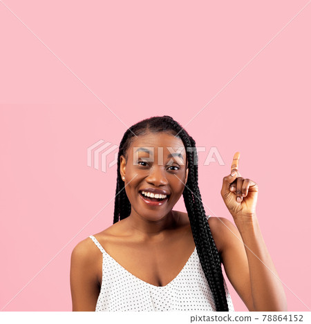 Smiling millennial black woman in white summer dress pointing upwards at empty space on pink studio background Smiling millennial black woman in white summer dress pointing upwards at empty space on pink studio background 78864152