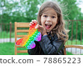 Caucasian little girl playing with pop it silicone trendy rainbow colow toy 78865223