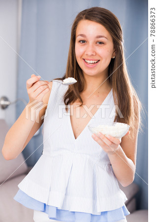 Cheerful female is enjoying tasty curd 78866373