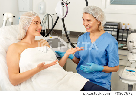 Doctor beautician discussing with woman cosmetological procedure in clinic Doctor beautician discussing with woman cosmetological procedure in clinic 78867672