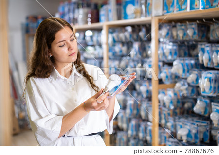 Woman choices energy saving lamp at hardware store 78867676