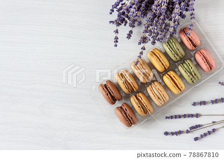 Multi colored french macaroons in a box top view on white wooden background. 78867810