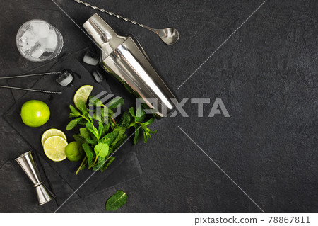 Ingredients and bar utensils for making mojito cocktail with ice cubes, fresh mint and lime on black background. 78867811