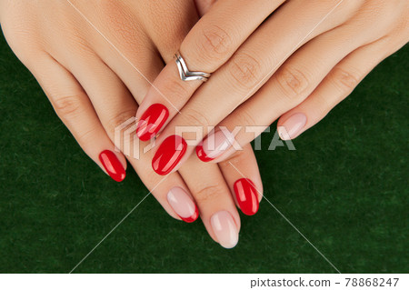 Womans hands with red modern manicure over green background. Manicure design trends. 78868247