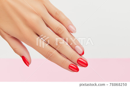 Womans hand with fashionable red manicure over white and pink background 78868250