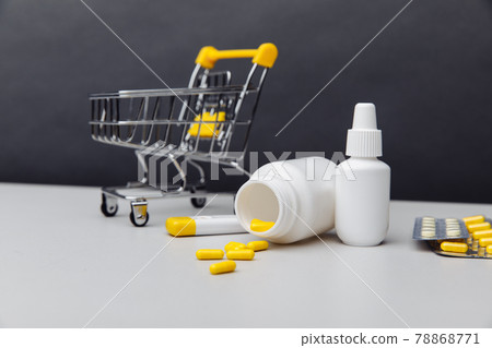 Shopping trolley with pills and medical tools on a grey backround Shopping trolley with pills and medical tools on a grey backround 78868771