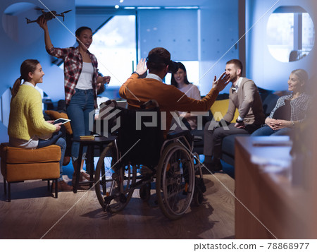 Disabled businessman in a wheelchair at work in modern open space coworking office with team using virtual reality googles drone assistance simulation 78868977
