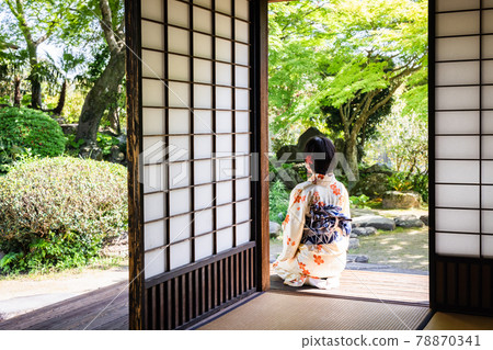 A young woman wearing a kimono and sitting on the porch 78870341