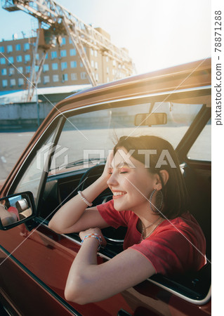 Smiling girl sitting at the car and looking at the window while chilling Smiling girl sitting at the car and looking at the window while chilling 78871288
