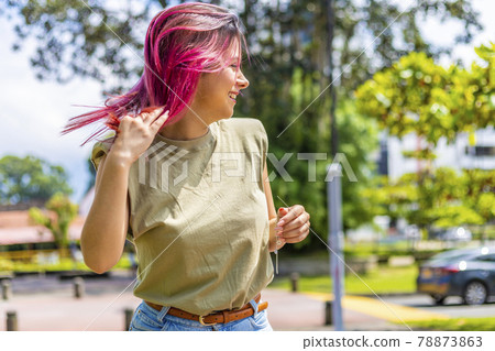 young latina in a park playing with her hair 78873863