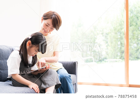 Mother supporting next to a girl learning online 78875458