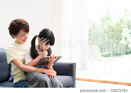 Mother hugging and watching over a girl learning online 78875761
