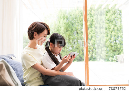 Mother hugging and watching over a girl learning online 78875762