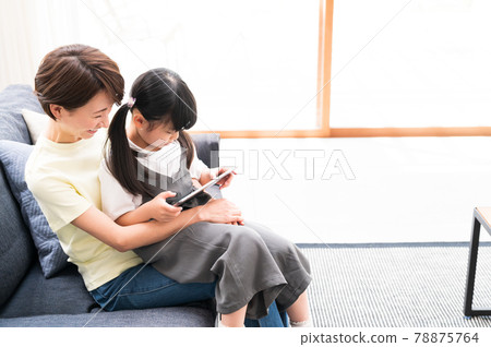 Mother hugging and watching over a girl learning online 78875764