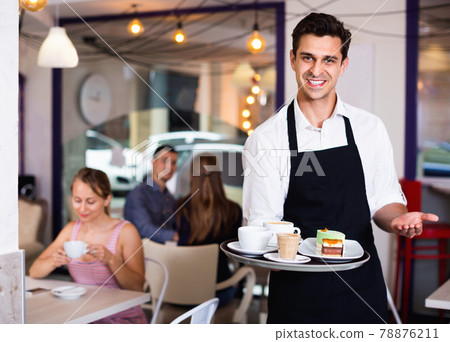 Waiter holding served tray meeting visitors at pastry bar 78876211