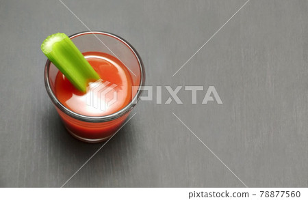 tomato juice in a glass with celery stick on gray wooden background tomato juice in a glass with celery stick on gray wooden background 78877560