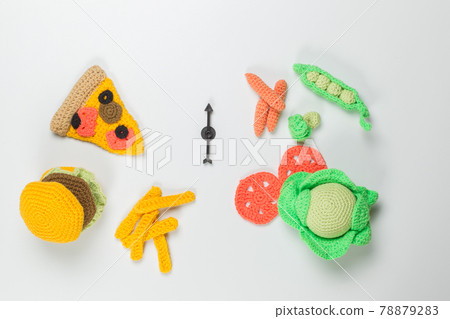 Children's toy knitted food. Pizza, hamburger and French fries on one side and vegetables on the other. Top view on a light background 78879283
