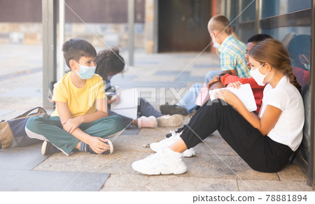 Elementary schoolchildren in masks talking outside 78881894