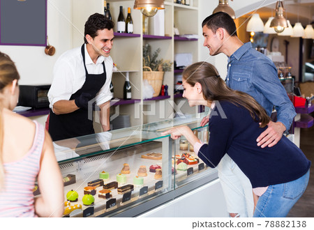 Couple with female friend are choosing delicious cakes from showcase Couple with female friend are choosing delicious cakes from showcase 78882138