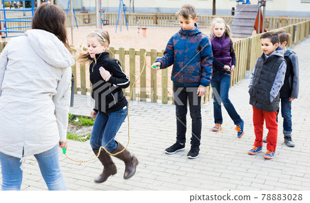 Children playing rubber band jumping game and laughing Children playing rubber band jumping game and laughing 78883028