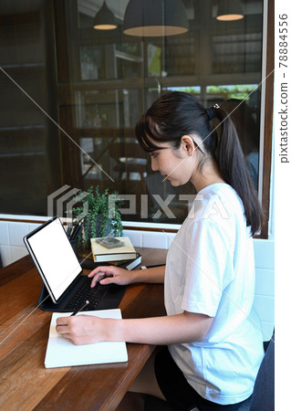 Side view of young female student studying online with tablet at home. 78884556