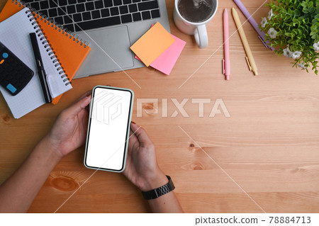 Above view woman holding mobile phone with empty display on wooden desk. 78884713
