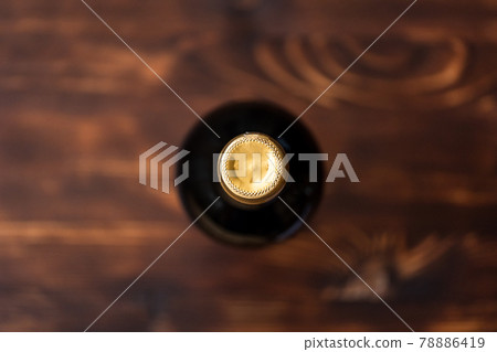 A dark bottle of wine blurry on a wooden background. 78886419