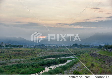 天空中朦朧的光亮，流動的雲彩漂浮在溪流中，上方是遠處的山峰。 78888513