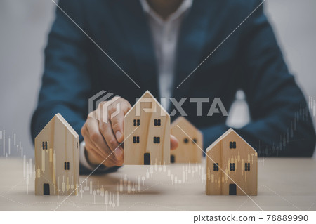 Man hand choosing mini wood house model from the model on wood table, Planning buy Real Estate, Planning to buy property. concept of Choose the best, Business market graph. 78889990