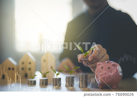 Hand hold Coins and pink piggy with icon business with Mini wood house model from model on wood table, Planning buy Real Estate, Planning to buy property and Choose the best, saving money concept. 78890026