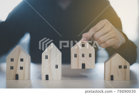 Man hand choosing mini wood house model from model on wood table, Planning buy Real Estate, Planning to buy property. concept of Choose the best. 78890030