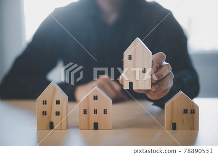 Man hand choosing mini wood house model from model on wood table, Planning buy Real Estate, Planning to buy property. concept of Choose the best. Man hand choosing mini wood house model from model on wood table, Planning buy Real Estate, Planning to buy property. concept of Choose the best. 78890531