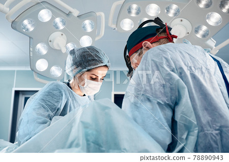 A team of male and female surgeons in a modern operating room, under a bright light, perform an operation, modern medicine. 78890943