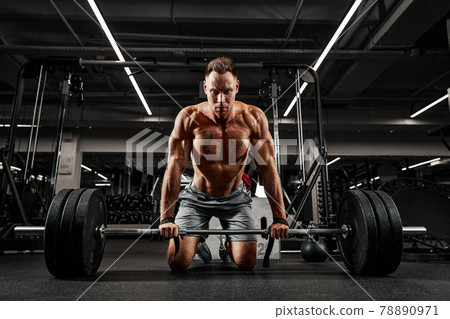 Atmospheric photo of an athlete with a barbell in a dark room, concentration, preparation for work with a large barbell weight Atmospheric photo of an athlete with a barbell in a dark room, concentration, preparation for work with a large barbell weight 78890971