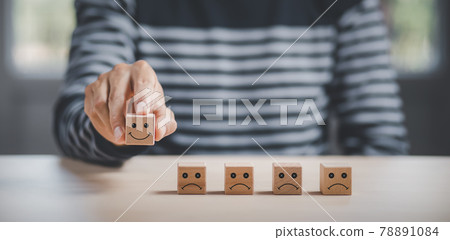Customer service evaluation and satisfaction survey service rating concepts.Hand choose wooden cube block with icon face smile, Close up customer hand choose the happy face smile face icon on wooden. 78891084