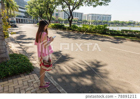 Young woman checking smart phone outdoors in sunny morning Young woman checking smart phone outdoors in sunny morning 78891211
