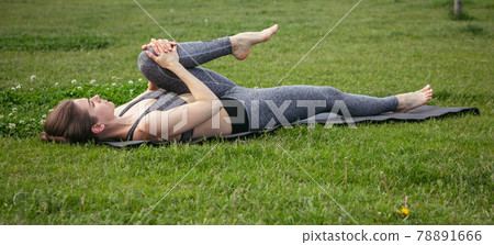 Young beautiful woman doing yoga exercise in green park near the pond. Exercices for improve the flexibility. Wellbeing and wellness. Young beautiful woman doing yoga exercise in green park near the pond. Exercices for improve the flexibility. Wellbeing and wellness. 78891666
