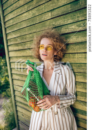 Picture of a young woman in sunglasses with a mesh bag Picture of a young woman in sunglasses with a mesh bag 78891822