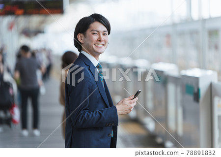 Image of young man commuting and IoT with a smartphone at the platform of the station Image of young man commuting and IoT with a smartphone at the platform of the station 78891832