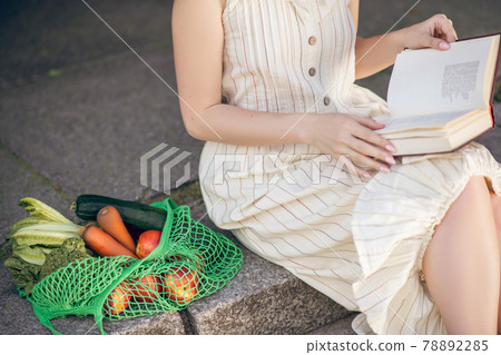 Woman sitting on the steps with a book in hands 78892285