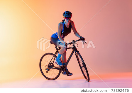 Cyclist riding a bicycle isolated against gradient light pink yellow neon background Cyclist riding a bicycle isolated against gradient light pink yellow neon background 78892476