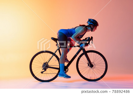 Female cyclist riding a bicycle isolated against neon background 78892486