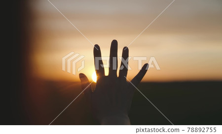 Reaching out to the sun, happy girl at sunset, sunlight shining on her hand, solar system star, happy family concept, touching a dream, asking for help from God, natural phenomenon 78892755