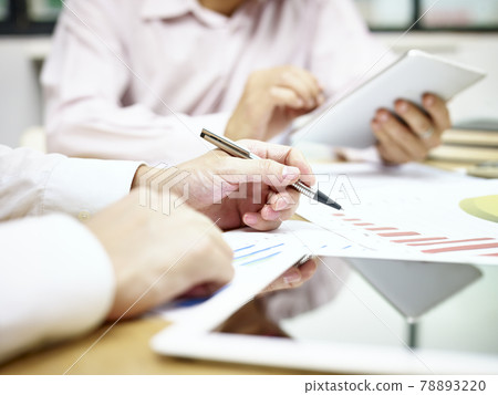 two business executives sitting at desk discussing sales performance using tablet computer two business executives sitting at desk discussing sales performance using tablet computer 78893220