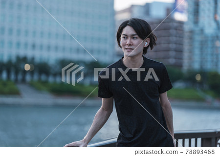 一個年輕人一邊聽音樂一邊準備慢跑 一個年輕人一邊聽音樂一邊準備慢跑 78893468