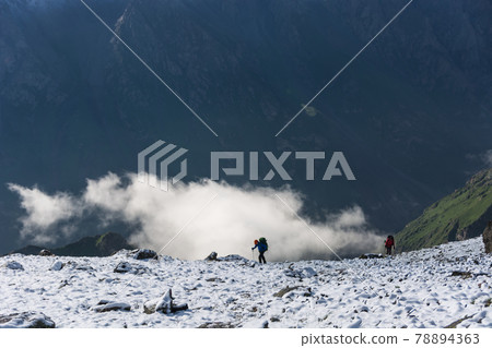 Idyllic winter landscape with hiking people in the mountains. Rocks, snow and stones in mountain valley view. Mountain panorama. Idyllic winter landscape with hiking people in the mountains. Rocks, snow and stones in mountain valley view. Mountain panorama. 78894363