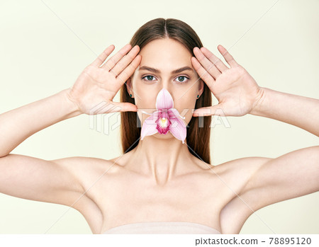 Beautiful young woman with orchid in her mouth make funny faces on studio background Beautiful young woman with orchid in her mouth make funny faces on studio background 78895120