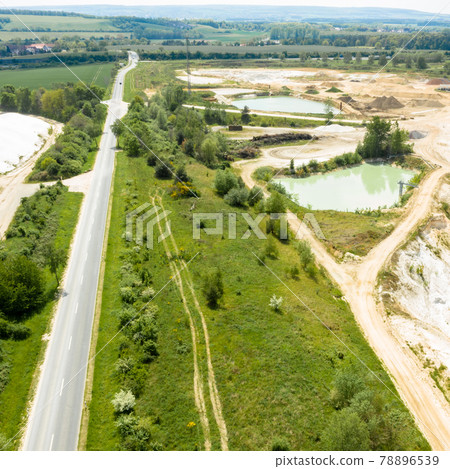 Aerial view of an asphalted meadow next to a meadow near the ponds of a sand mining company, industry 78896539