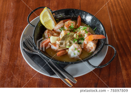 Shrimps in a metal plate stewed in sauce with a slice of lemon. Traditional Portuguese cuisine. Mediterranean Culture. Top view. Shrimps in a metal plate stewed in sauce with a slice of lemon. Traditional Portuguese cuisine. Mediterranean Culture. Top view. 78897809